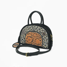 Load image into Gallery viewer, Tiara black suede dome satchel with beaded arch and hand-tooled floral panel, angled view with strap
