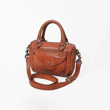 Load image into Gallery viewer, Angled view of the Clementine studded cognac leather satchel with rolled top handles, snap-flap pocket, and detachable crossbody strap
